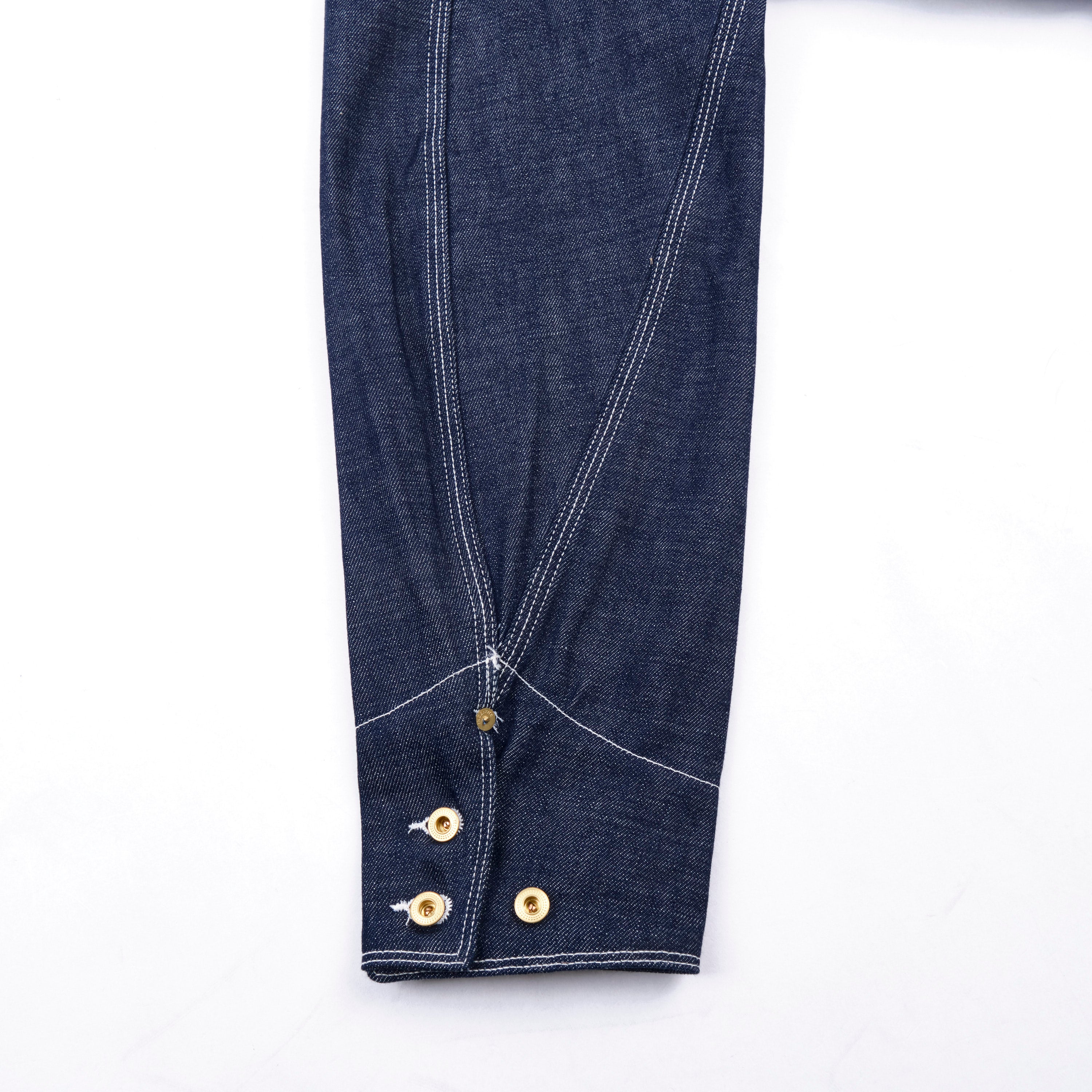 Close-up of blue denim fabric with gold buttons on a white background